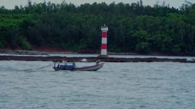 Küçük balıkçı tekneleri ve deniz ağzında ileri geri koşan Vietnamlı balıkçı tekneleri olan deniz burnu. Sa Ky haliçleri, Quang Ngai. Denizde çalışmak. Tekneler yelken açtı. Deniz feneri. 
