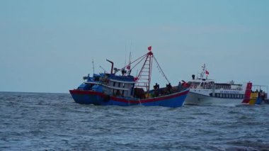 Quang Ngai, Vietnam - 8 Haziran 2023: Balıkçı gemileri ve balıkçı teknelerinin denize açılma görüntüleri. An Vinh Ekspres yüksek hızlı nakliye treni Sa Ky sahnesine doğru ilerliyor.
