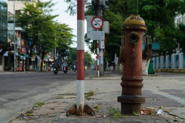 Quang Ngai, Vietnam - Haziran 2023: Bir itfaiye vanası yol kenarında trafik işaretinin yanında çalışmayı durdurdu. İtfaiyeci ikonu, yaşlı.