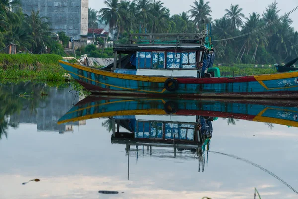 stock image A Vietnamese fisherman's fishing boat is moored on a calm river with a reflection on the water.