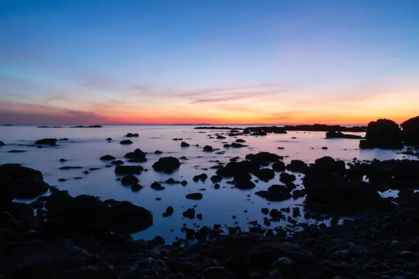 Akıntıda deniz manzarası ve şafağın sarı ve mavi bulutlarıyla alacakaranlık gökyüzü. Doğa denizi ve mavi gökyüzü gün doğumu ve gün batımı.