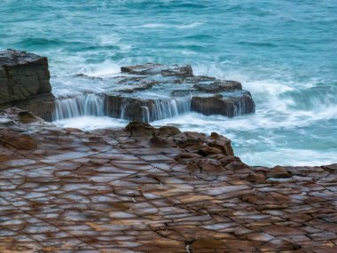 Merkezi Sahildeki North Avoca Sahili 'ndeki tessellated kaya platformunun üzerinde hava gündoğumu deniz manzarası, NSW, Avustralya.