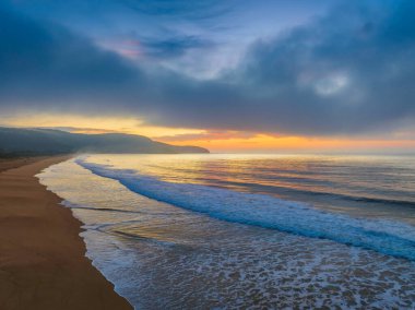 Deniz kıyısında, yumuşak bulut ve sisle birlikte hava gündoğumu Central Coast, NSW, Avustralya 'daki Killcare Plajı' nda ilerliyor..