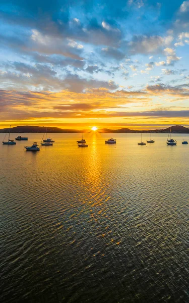 Sun rising over Brisbane Water with clouds and boats at Koolewong and Tascott on the Central Coast, NSW, Australia.
