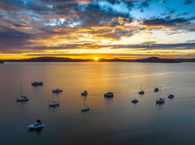 Brisbane Suyu 'nda yükselen güneş bulutları ve botlarla Koolewong ve Tascott' ta merkez kıyısı, NSW, Avustralya 'da..