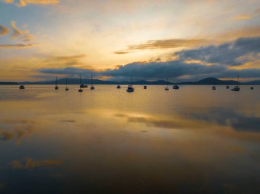 Brisbane üzerinde yumuşak ve rüya gibi bir gün doğumu bulutlu, sisli ve tekneli Koolewong ve Tascott 'ta merkez sahilinde, NSW, Avustralya.