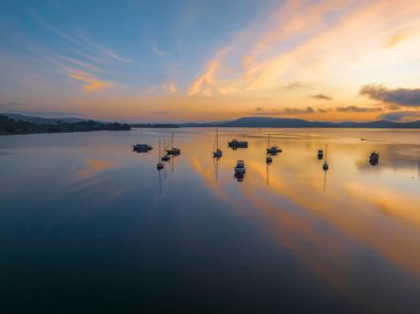 Brisbane üzerinde yumuşak ve rüya gibi bir gün doğumu bulutlu, sisli ve tekneli Koolewong ve Tascott 'ta merkez sahilinde, NSW, Avustralya.