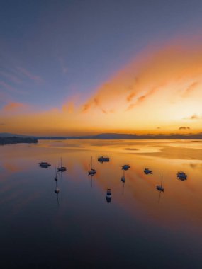 Brisbane üzerinde yumuşak ve rüya gibi bir gün doğumu bulutlu, sisli ve tekneli Koolewong ve Tascott 'ta merkez sahilinde, NSW, Avustralya.