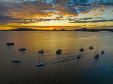 Brisbane üzerinde güneş doğuyor bulutlar ve tekneler Koolewong 'da ve Tascott' ta merkez sahilde, NSW, Avustralya.
