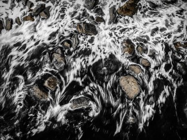 Orta Sahildeki Avoca Sahili, NSW, Avustralya 'da kayalar ve kahverengi ipuçları içeren siyah ve beyaz deniz manzarası..