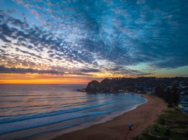 Deniz kıyısında hava güneşinin doğuşu. Orta büyüklükteki bulutlar gökyüzünde yayılıyor. Orta Sahildeki Avoca Sahili, NSW, Avustralya..