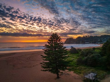 Deniz kıyısında hava güneşinin doğuşu. Orta büyüklükteki bulutlar gökyüzünde yayılıyor. Orta Sahildeki Avoca Sahili, NSW, Avustralya..