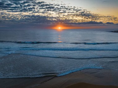 Orta büyüklükteki bulutlarla birlikte deniz kıyısında hava gündoğumu Orta Sahildeki Avoca Sahili 'nde, NSW, Avustralya.