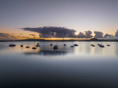 Gündoğumu, bulutlar ve tekne yansımaları Brisbane 'de Koolewong' da ve Tascott 'ta merkez sahilde, NSW, Avustralya.