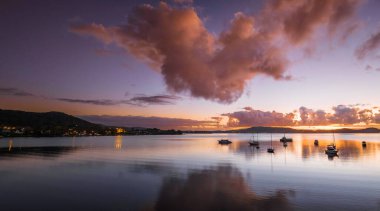 Gündoğumu, bulutlar ve tekne yansımaları Brisbane 'de Koolewong' da ve Tascott 'ta merkez sahilde, NSW, Avustralya.
