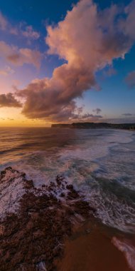 Central Coast, NSW, Avustralya 'daki North Avoca Sahili' nde bulutlu, kaya platformlu, dalgalı ve plajlı hava gündoğumu deniz manzarası.