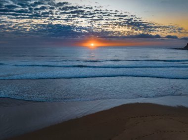 Orta büyüklükteki bulutlarla birlikte deniz kıyısında hava gündoğumu Orta Sahildeki Avoca Sahili 'nde, NSW, Avustralya.