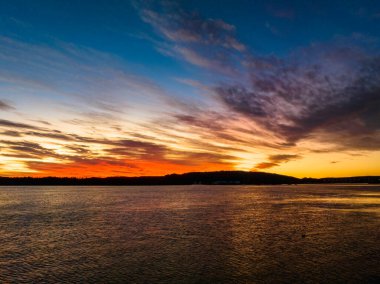 Woy Woy körfezinde, NSW, Avustralya 'da yüksek bulutlu hava gündoğumu su manzarası..