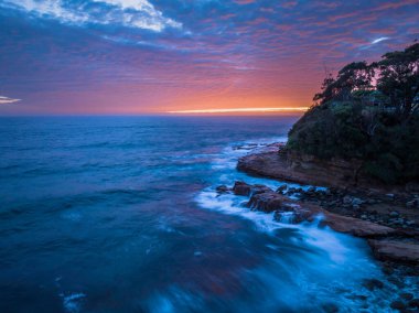 Central Coast, NSW, Avustralya 'daki Avoca Sahili' nde bulutlu, sörf ve atmosferli gün doğumu deniz manzarası.