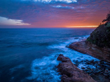 Central Coast, NSW, Avustralya 'daki Avoca Sahili' nde bulutlu, sörf ve atmosferli gün doğumu deniz manzarası.