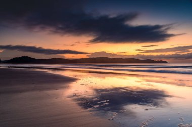 Subtle summer sunrise with rain clouds in  the distance at Umina Beach on the Central Coast, NSW, Australia.