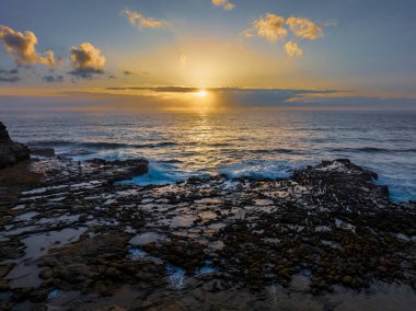 Central Coast, NSW, Avustralya 'daki Kuzey Avoca' da güneş, bulutlar ve kaya platformu ile gün doğumu deniz manzarası.