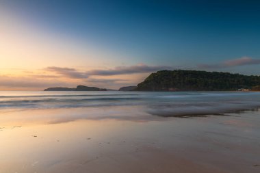 Subtle summer sunrise with rain clouds in  the distance at Umina Beach on the Central Coast, NSW, Australia.