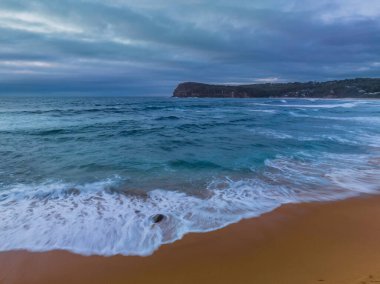 Central Coast, NSW, Avustralya 'daki Copacabana' da serin bir sabahta bulutlarla birlikte gün doğumu denizi..