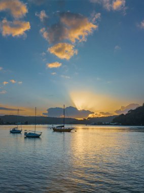 Sunrise over Brisbane Water with clouds and boats at Ettalong Beach on the Central Coast, NSW, Australia.