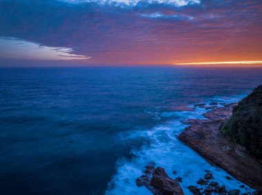 Central Coast, NSW, Avustralya 'daki Avoca Sahili' nde bulutlu, sörf ve atmosferli gün doğumu deniz manzarası.