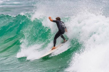Surf's up - Male surfer catching a wave at Avoca Beach on the Central Coast of NSW, Australia