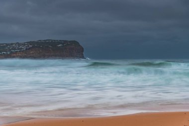 Sunrise with rain clouds and good sized waves at  Macmasters Beach on the Central Coast, NSW, Australia.