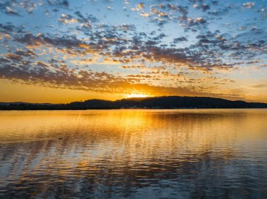 Körfezin üzerinde gökyüzünü boyayan altokümülüs bulutlarıyla birlikte havadan gün doğumu Central Coast, NSW, Avustralya 'da..