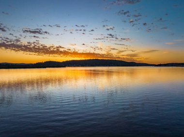 Körfezin üzerinde gökyüzünü boyayan altokümülüs bulutlarıyla birlikte havadan gün doğumu Central Coast, NSW, Avustralya 'da..