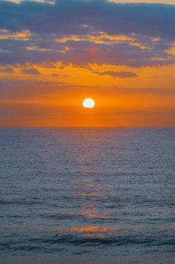 Early morning sun peaking over the clouds at Avoca Beach on the Central Coast, NSW, Australia.