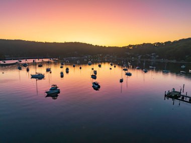 Sunrise, boats and a cloudless sky at Hardys Bay on the Central Coast, NSW, Australia.
