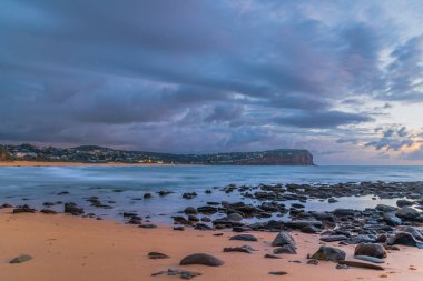 Central Coast, NSW, Avustralya 'daki Macmaster Sahili' nde yağmur bulutları ve deniz havuzu ile gün doğumu..