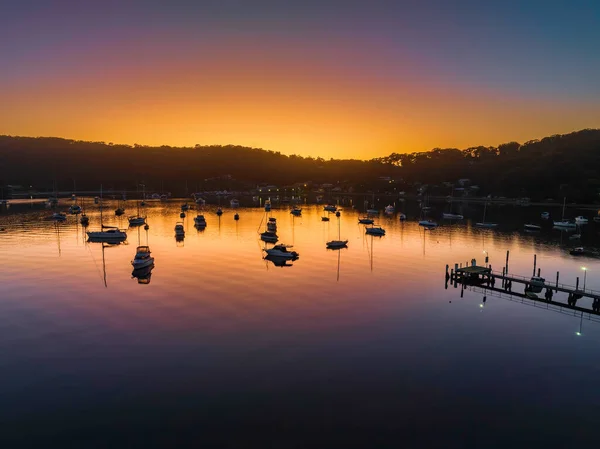 Sunrise, boats and a cloudless sky at Hardys Bay on the Central Coast, NSW, Australia.
