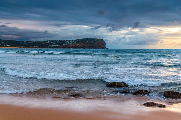 stock image Sunrise seascape with rain clouds and rocks at Macmasters Beach on the Central Coast, NSW, Australia.