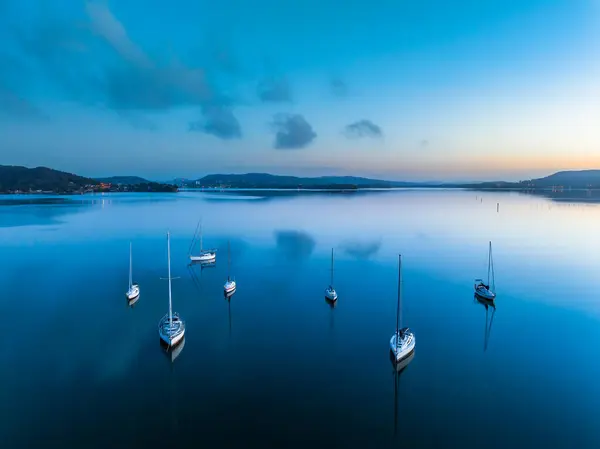 stock image A still sunrise over Brisbane Water with boats. clouds and reflections at Koolewong on the Central Coast, NSW, Australia.