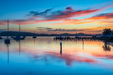 Gündoğumu, Brisbane 'deki teknelerle birlikte Central Coast, NSW, Avustralya' daki Koolewong 'da yansıyor..