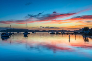 Gündoğumu, Brisbane 'deki teknelerle birlikte Central Coast, NSW, Avustralya' daki Koolewong 'da yansıyor..