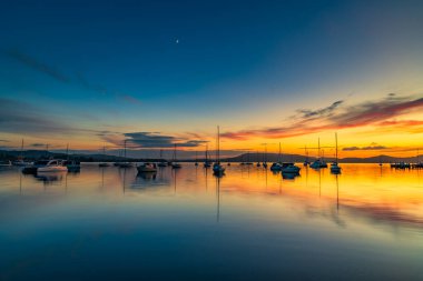 Gündoğumu, Brisbane 'deki teknelerle birlikte Central Coast, NSW, Avustralya' daki Koolewong 'da yansıyor..