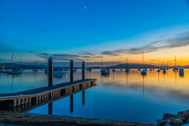 Sunrise reflections with boats on Brisbane Water at Koolewong on the Central Coast, NSW, Australia. clipart