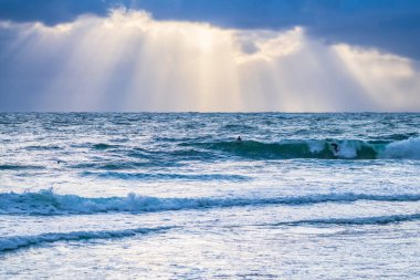 Yağmurlu gün doğumu bulutlu gökyüzü, güneş ışınları ve dalgalar Orta Sahildeki Macmaster Sahili, NSW, Avustralya.