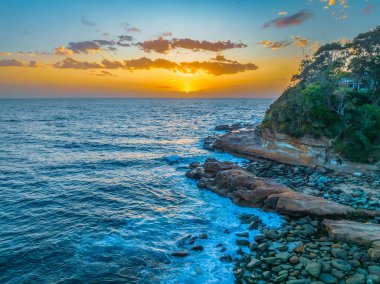 Gündoğumu deniz manzarası bulutlu ve kayalıklı Avoca Sahili 'nde merkez kıyısı, NSW, Avustralya.