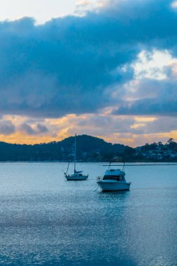 Gündoğumu, bulutlar, tekneler ve yansımalar Brisbane üzerinde Koolewong 'da ve Tascott' ta merkez sahilde, NSW, Avustralya.