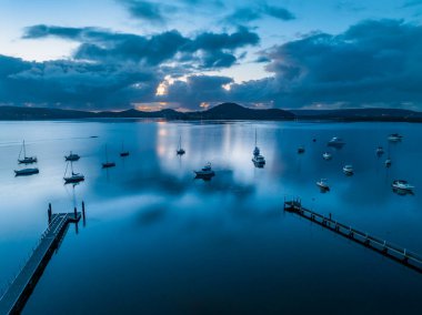 Sunrise, clouds, boats and reflections over Brisbane Water at Koolewong and Tascott on the Central Coast, NSW, Australia. clipart