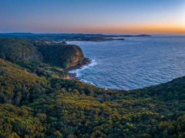 Avustralya, NSW 'nin merkez kıyısındaki Copacabana' daki Kaptan Cook Gözcüsünden deniz ve orman üzerindeki gün doğumu manzarası.