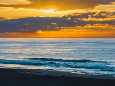 Orta Sahildeki Avoca Sahili, NSW, Avustralya 'daki deniz ve lagünün gündoğumu görüntülerini izliyorum..